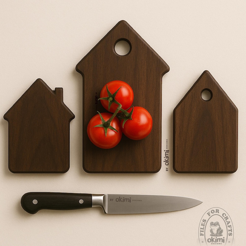 Puede incluir: Un conjunto de tres tablas de cortar de madera con forma de casa y un cuchillo de acero inoxidable con mango negro. Tres tomates rojos descansan sobre la tabla central. Las tablas son de color marr&oacute;n oscuro y el cuchillo tiene el texto "by okimi designs".