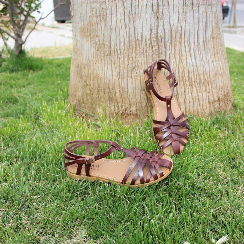Fisherman flat sandal with soft leather insole, 6 thin criss-cross straps in front, longer waist strap  from closed toes to ankle and adjustable ankle strap that closes and fastens with a metal buckle. Τhe heel is closed with thin straps.rubber sole