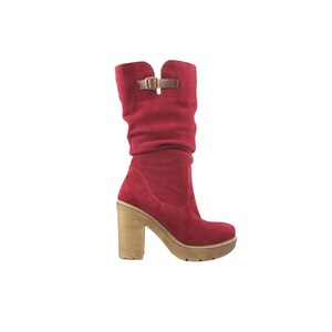 May include: Red suede heeled boots with a buckle detail and a wooden heel.