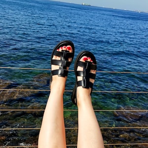 May include: A pair of black leather sandals with a criss-cross strap design. The sandals have a comfortable, open-toe design and are perfect for warm weather.