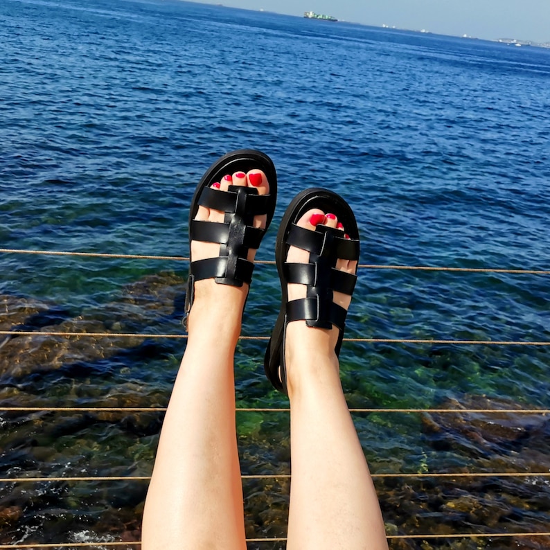 May include: A pair of black leather sandals with a criss-cross strap design. The sandals have a comfortable, open-toe design and are perfect for warm weather.