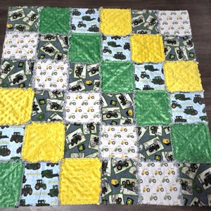 Könnte beinhalten: Eine Patchwork-Decke mit Quadraten aus grünen, gelben und gemusterten Stoffen. Die Muster zeigen Traktoren auf weißen, blauen und grauen Hintergründen. Die Decke hat ein weiches, strukturiertes Aussehen.