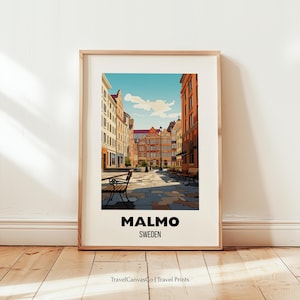 May include: Framed art print of a street scene in Malmo, Sweden. The artwork features colorful buildings, benches, and a cobblestone street under a blue sky. The word "MALMO" and "SWEDEN" are printed in black at the bottom.
