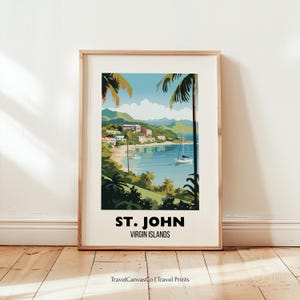 Op de afbeelding: Een ingelijste kunstdruk met een kustlandschap van St. John, Maagdeneilanden. Het kunstwerk toont een baai met zeilboten, weelderige groene vegetatie en gebouwen onder een blauwe lucht. De tekst "ST. JOHN VIRGIN ISLANDS" staat onderaan.