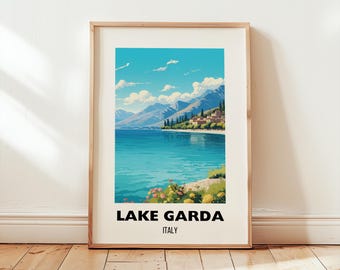 May include: A framed art print featuring a scenic view of Lake Garda, Italy. The artwork depicts a turquoise lake, mountains, and a village under a bright blue sky with clouds. The text "LAKE GARDA ITALY" is displayed at the bottom.