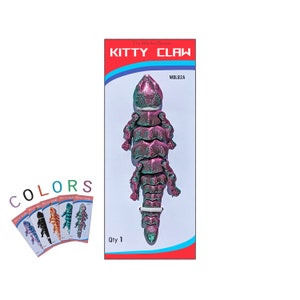 May include: A pink and green Kitty Claw cat toy with a white ring. The packaging says "The Whisker Bros. Kitty Claw" and "WBLB2A".