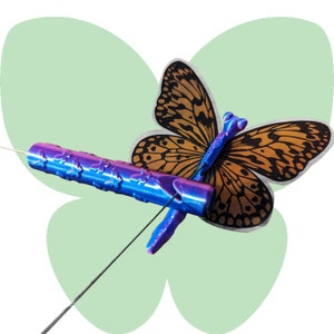 May include: A blue and purple butterfly pin with a black and brown butterfly design. The pin is attached to a thin wire.