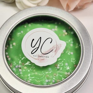 Könnte beinhalten: Eine runde, silberne Dose gefüllt mit hellgrünem Schleim. Der Schleim ist mit kleinen, bunten Perlen übersät. Ein weißer Aufkleber mit den Buchstaben "YC" und den Worten "YVI CREATION" befindet sich auf dem Schleim.