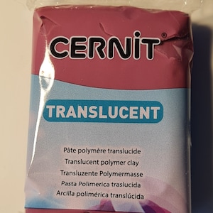 May include: A package of translucent polymer clay by Cernit. The package is pink and has the text "CERNIT TRANSLUCENT" on the front. The text "Pâte polymère translucide, Translucent polymer clay, Transluzente Polymermasse, Pasta Polimerica traslucida, Arcilla polimérica translúcida" is printed on the front of the package.