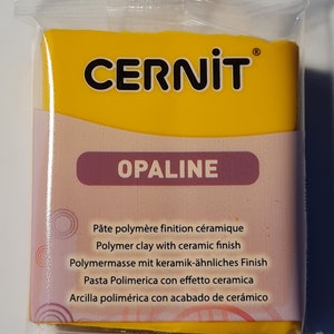 Może przedstawiać: Żółte opakowanie gliny polimerowej CERNIT OPALINE z ceramicznym wykończeniem. Opakowanie zawiera tekst w języku francuskim, angielskim, niemieckim, włoskim i hiszpańskim.