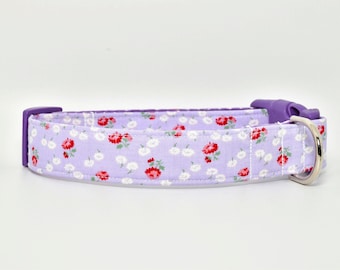 May include: A lavender dog collar with a white and red floral pattern. The collar has a purple plastic buckle and a silver metal D-ring.