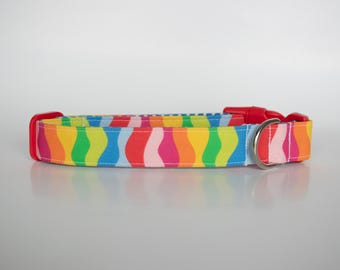 Puede incluir: Un collar de perro colorido con un patrón de ondas arcoíris. El collar es rojo con una hebilla plateada.
