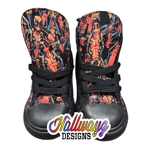 May include: Black high-top sneakers with a red and black Deadpool print. The shoes have black laces and a black rubber sole.