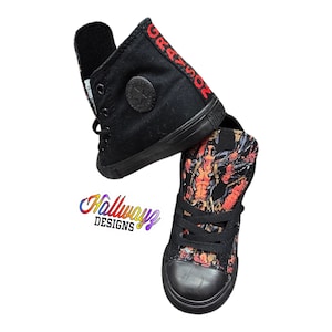 May include: Two pairs of black high-top sneakers. One pair has a black canvas with the word "GRAZIOR" embroidered in red on the side. The other pair has a black canvas with a colorful graphic print.