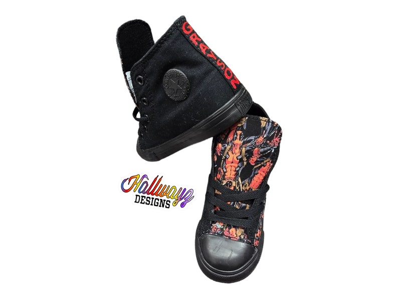 May include: Two pairs of black high-top sneakers. One pair has a black canvas with the word "GRAZIOR" embroidered in red on the side. The other pair has a black canvas with a colorful graphic print.
