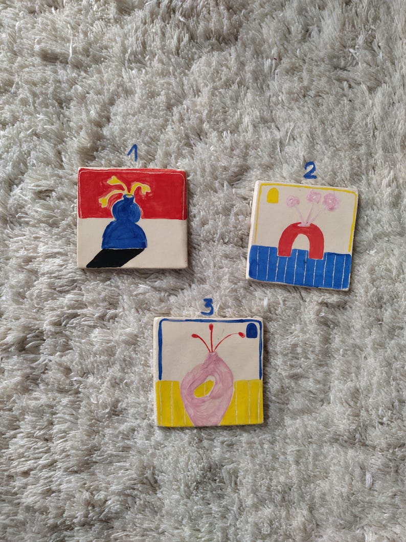 May include: Three ceramic tiles with colorful abstract floral designs. Each tile features a different vase shape and floral arrangement in shades of red, yellow, blue, and pink.