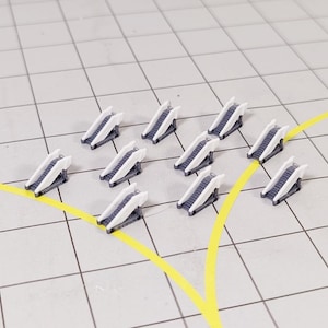 May include: Miniature white and grey escalators are arranged on a grid, with yellow lines. The escalators have a detailed design. The background is a white grid.
