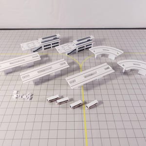May include: A white model train set with multiple track pieces, including straight tracks, curved tracks, and a station platform. The set also includes four small white train carriages.