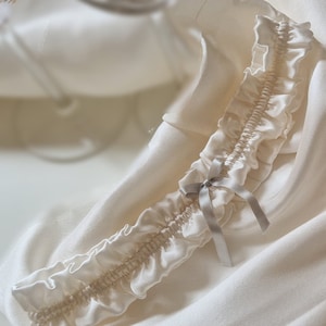 Soft white, pure silk wedding garter adorned with a graceful silver silk bow at its centre.