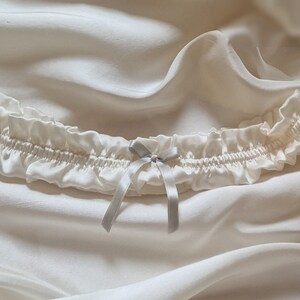 Soft white, pure silk wedding garter adorned with a graceful silver silk bow at its centre.