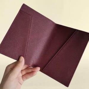 Hand holding interior view of the passport cover in burgundy.