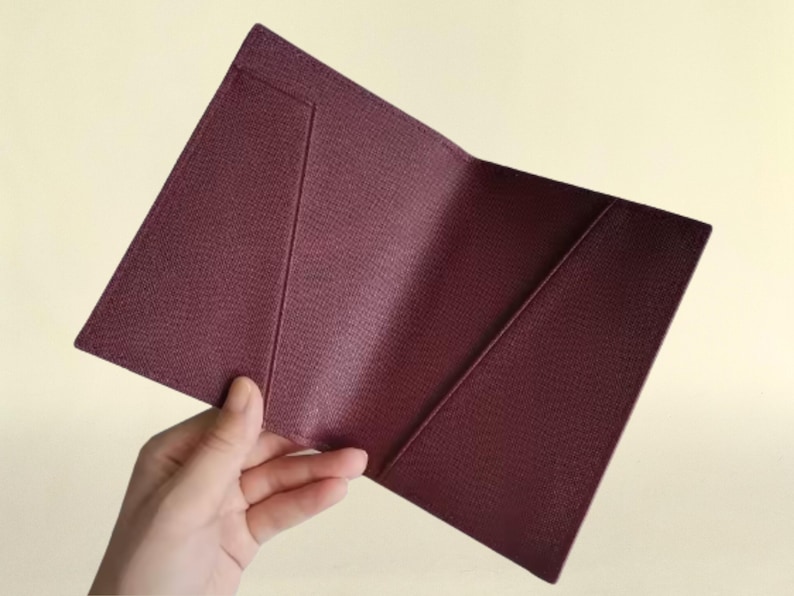 Hand holding interior view of the passport cover in burgundy.