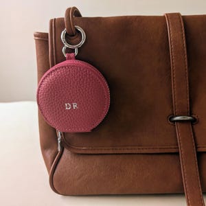 Monogrammed pink wallet keyring attached to a leather purse.