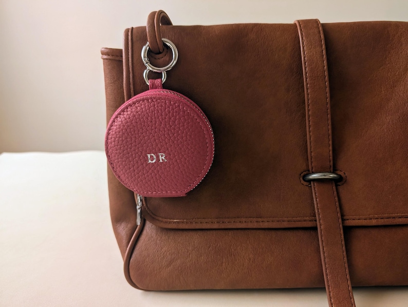 Monogrammed pink wallet keyring attached to a leather purse.