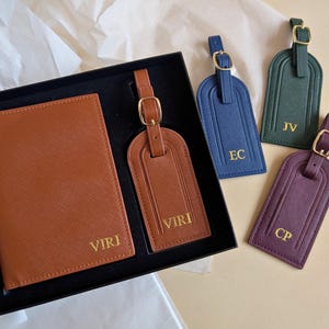 A brown passport cover and luggage tag set in a black gift box with the name VIRI embossed in gold next to luggage tags showing other colors: navy, green, and burgundy all with gold embossing.