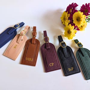 Custom intitial luggage tags fanned out in blue, blush, brown, burgundy, black and green.