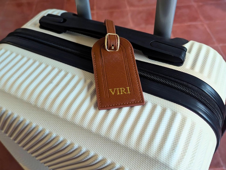 Brown luggage tag on a suitcase with custom initials.
