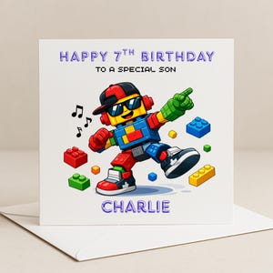May include: A birthday card with a cartoon robot made of building blocks, wearing sunglasses and a cap. The card reads "Happy 7th Birthday to a Special Son" and is personalised with the name "Charlie". Musical notes and building blocks are scattered around the robot.