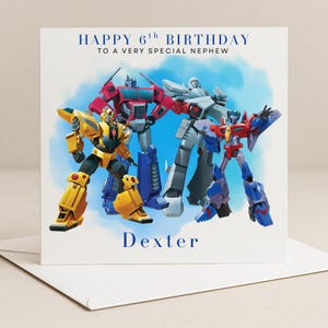 May include: A birthday card with a group of Transformers characters in various colours against a blue sky. The card reads "HAPPY 6th BIRTHDAY TO A VERY SPECIAL NEPHEW" and is personalised with the name "Dexter".