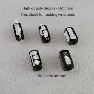 May include: Five black rectangular blocks with white text and designs. The blocks have the words "Alpha in greek", "ICE COLD", "Phi BZ", "Omega", and "Kappa". The text "Hole size 4mm" is also visible. The blocks are for making wristbands.