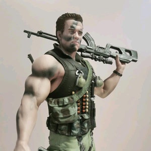 Puede incluir: Una figura de acción verde y negra de un soldado con un chaleco de camuflaje y un rifle colgado del hombro. La figura tiene la cara pintada con marcas de camuflaje negro y blanco.