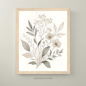 Puede incluir: Una impresión de arte mural enmarcada que presenta una ilustración botánica de flores silvestres y hojas en tonos apagados de gris, beige y verde suave. La obra está centrada en un marco de madera clara con el texto CREATIONS OF PKB debajo.