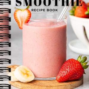 Puede incluir: Un batido rosa en un vaso con una pajita de metal, adornado con una rodaja de fresa. El batido se encuentra sobre una tabla de madera con rodajas de plátano y una fresa entera. La portada del libro de recetas dice "Weight Gain SMOOTHIE RECIPE BOOK".