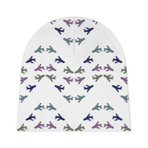 May include: White baby beanie hat featuring a repeating pattern of small aeroplanes in shades of blue, green, and purple. The planes are arranged in a symmetrical design across the hat's surface.