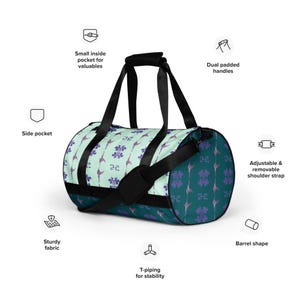 May include: A teal and light green duffel bag with a floral pattern. The bag has a black shoulder strap, two black handles, and a side pocket. It also has a small inside pocket for valuables. The bag is made of sturdy fabric and has T-piping for stability.