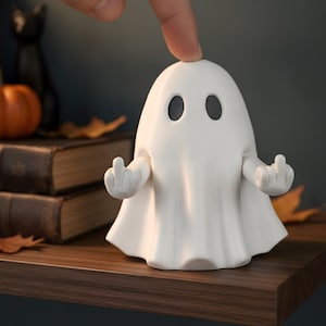 Könnte beinhalten: Eine weiße Geisterfigur mit zwei schwarzen, ovalen Augen und beweglichen Armen, die nach außen gestreckt sind, wobei beide Hände den Mittelfinger zeigen. Der Geist hat eine glatte, matte Oberfläche und ein tuchartiges Aussehen.