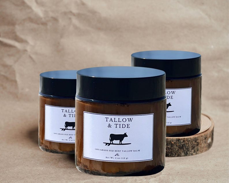 May include: Three glass jars of Tallow & Tide 100% Grass-Fed Beef Tallow Balm with black lids. Each jar has a white label with the brand name, a cow illustration, and the net weight of 4 oz (113 g).