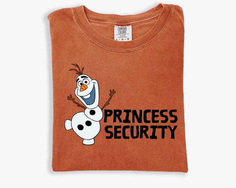 May include: A rust-colored t-shirt featuring a cartoon image of Olaf the snowman with the text "PRINCESS SECURITY" in black. The shirt is folded and has a Comfort Colors tag.