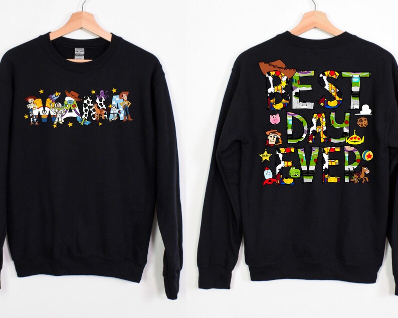 Puede incluir: Sudadera negra con tem&aacute;tica de Toy Story. La parte delantera presenta la palabra "WAMA" deletreada con personajes de Toy Story. La parte trasera presenta el texto "BEST DAY EVER" deletreado con personajes de Toy Story.