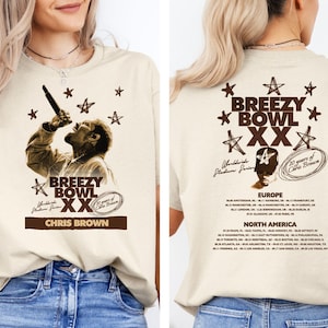 May include: Beige t-shirt featuring a sepia-toned image of a singer with the text "Breezy Bowl XX Chris Brown" on the front. The back of the shirt has the text "Breezy Bowl XX" and a list of tour dates.