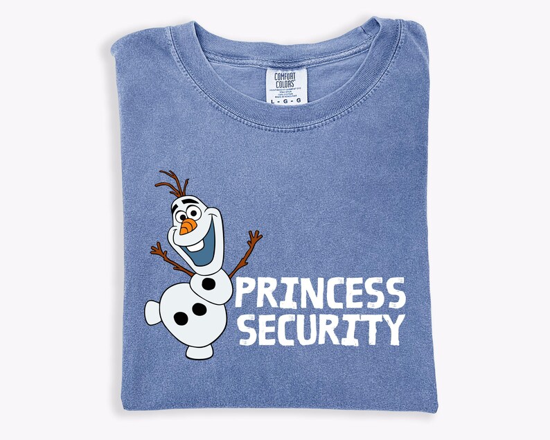 May include: A blue t-shirt with a graphic of Olaf the snowman and the words "PRINCESS SECURITY" in white. The shirt is folded and has a Comfort Colors tag at the neckline.