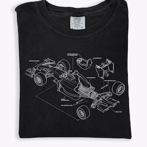 May include: Black t-shirt featuring a detailed white diagram of a Formula 1 race car, showcasing its components. The design includes labels like "Front Wing Assembly" and "Rear Suspension Arm." The shirt is made by Comfort Colors.