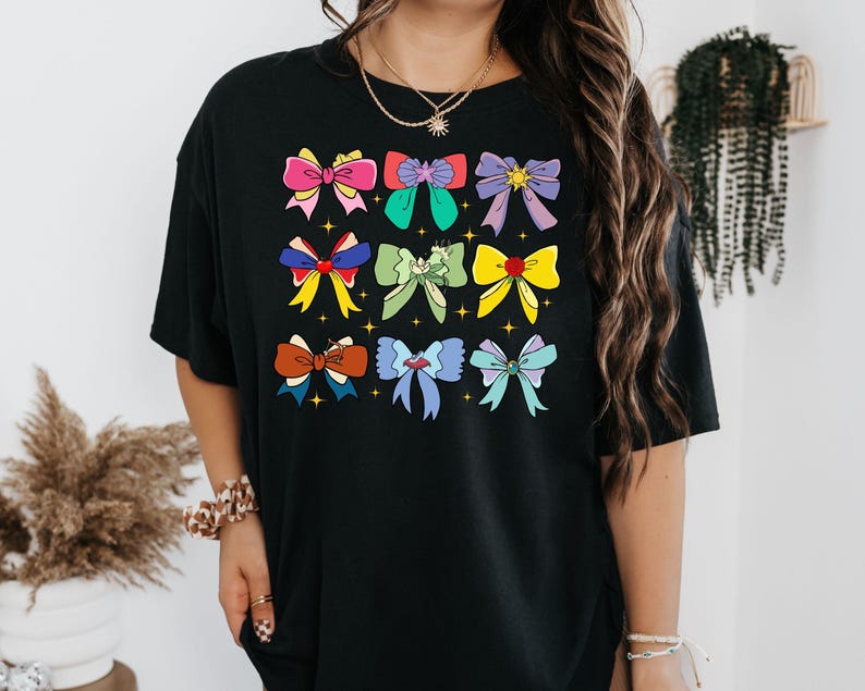 May include: Black t-shirt with a colorful graphic of bows. The bows are in various colors and patterns, including pink, blue, green, yellow, and purple.