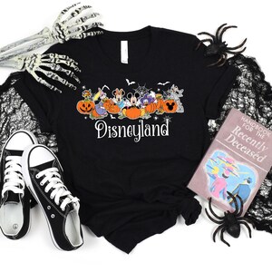 May include: Black t-shirt with a graphic of Mickey Mouse and friends dressed in Halloween costumes. The text "Disneyland" is printed below the graphic.