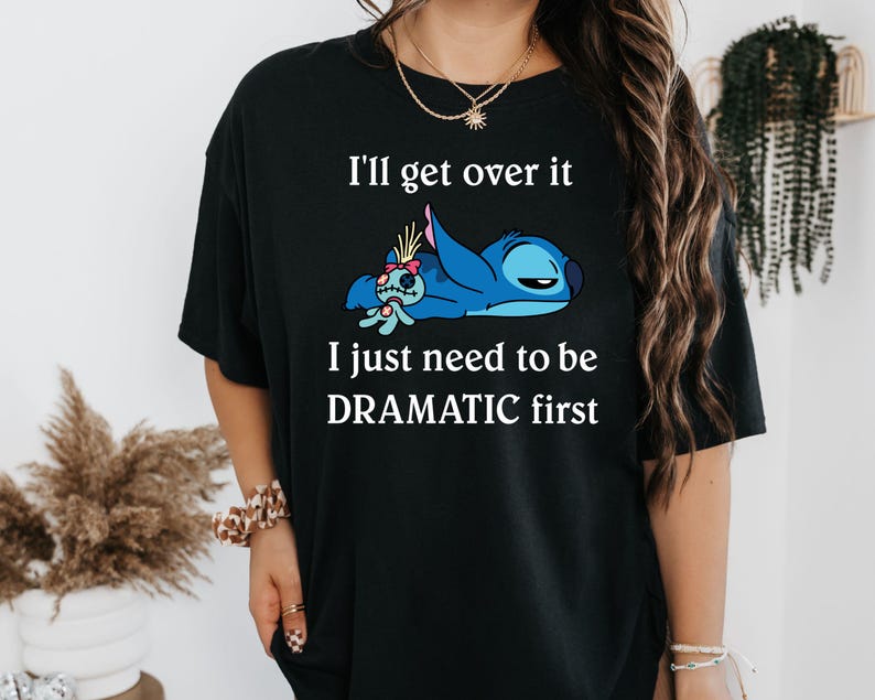 May include: Black t-shirt featuring a blue Stitch character from Lilo & Stitch. The text on the shirt reads "I'll get over it I just need to be DRAMATIC first."