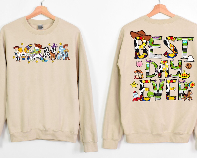 Puede incluir: Una sudadera de color beige con tem&aacute;tica de Toy Story. La parte delantera de la sudadera dice "Mama" con personajes de Toy Story. La parte trasera de la sudadera dice "Best Day Ever" con personajes de Toy Story.